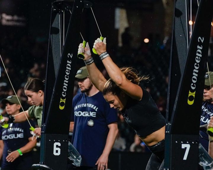 Individuals participating in a rowing machine competition, focusing on athletes pulling handles on Concept2 rowing machines.