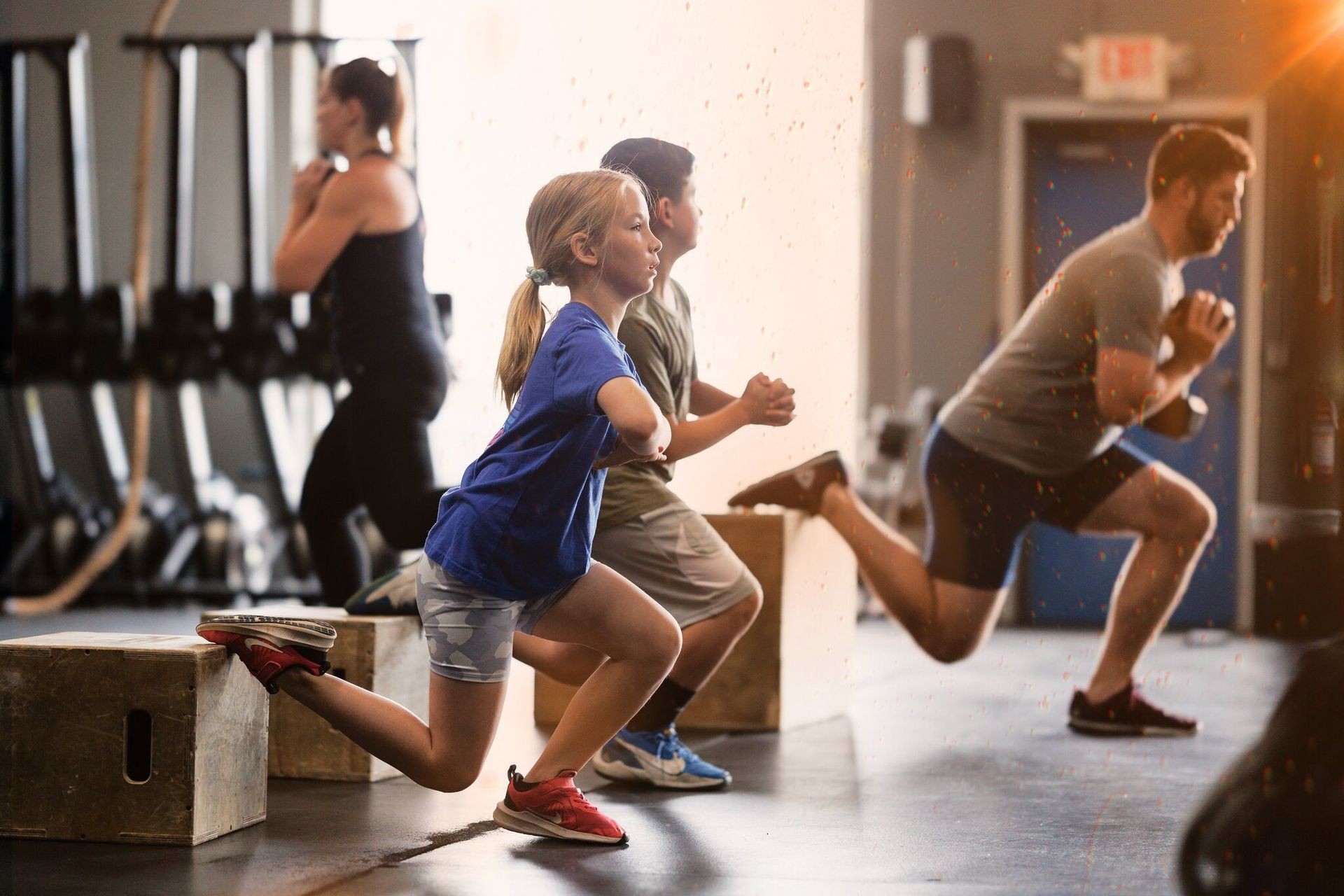 Group of people doing lunges during a fitness class in a gym setting.