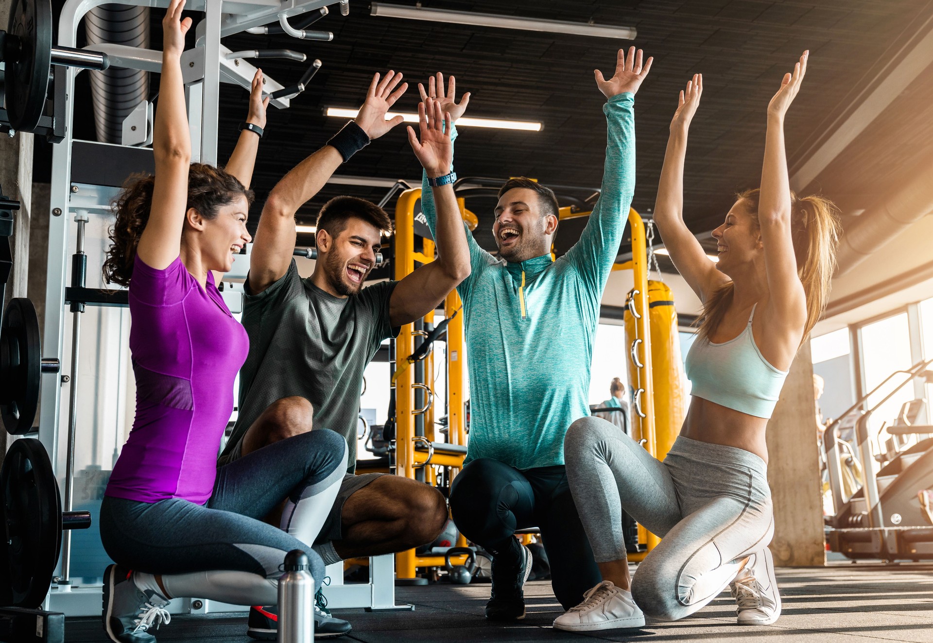Groupe de beaux jeunes faisant preuve d’esprit d’équipe tout en faisant de l’exercice ensemble dans un centre de remise en forme